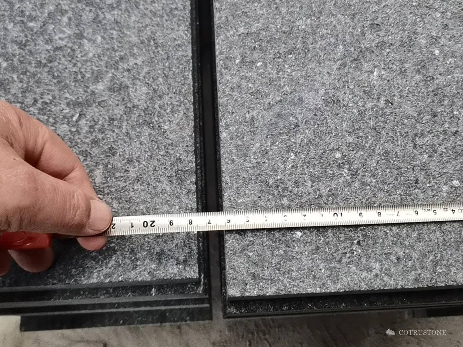 Measuring tape across a grey stone stair component
