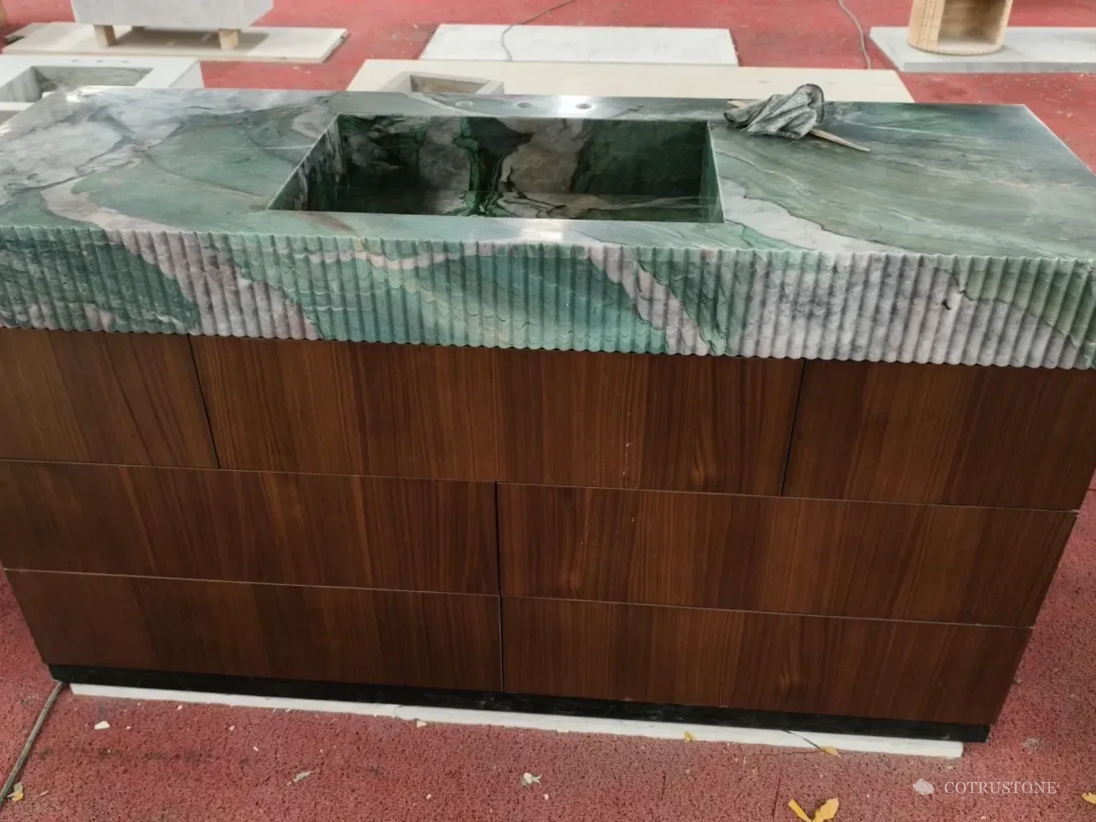 Green veined stone integrated basin with a reeded front above a dark wood cabinet in the workshop