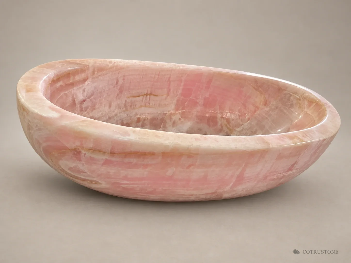 Pink onyx bathtub with a rounded bowl and broad rim